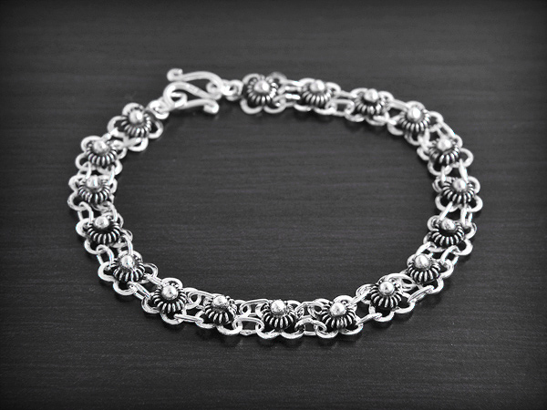 Joli bracelet en argent avec une maille aérée ornée de petites fleurs en volume (largeur:7mm).