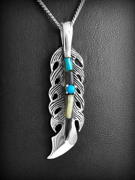 Pendentif en argent d'une belle plume en volume parée de turquoise et nacre (h:40mm).